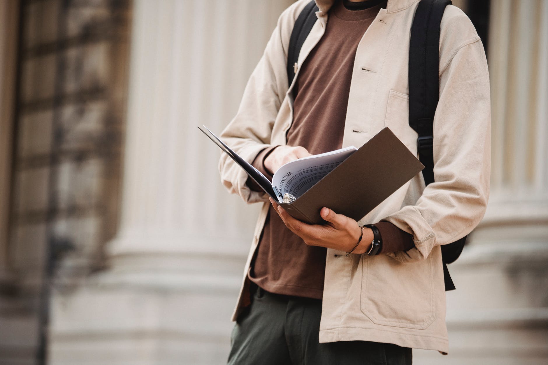 student reading documents in folder outside university